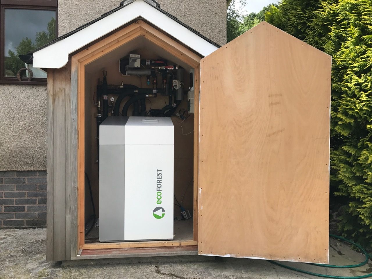 Ground source heat pump housed in a timber enclosure beside a house