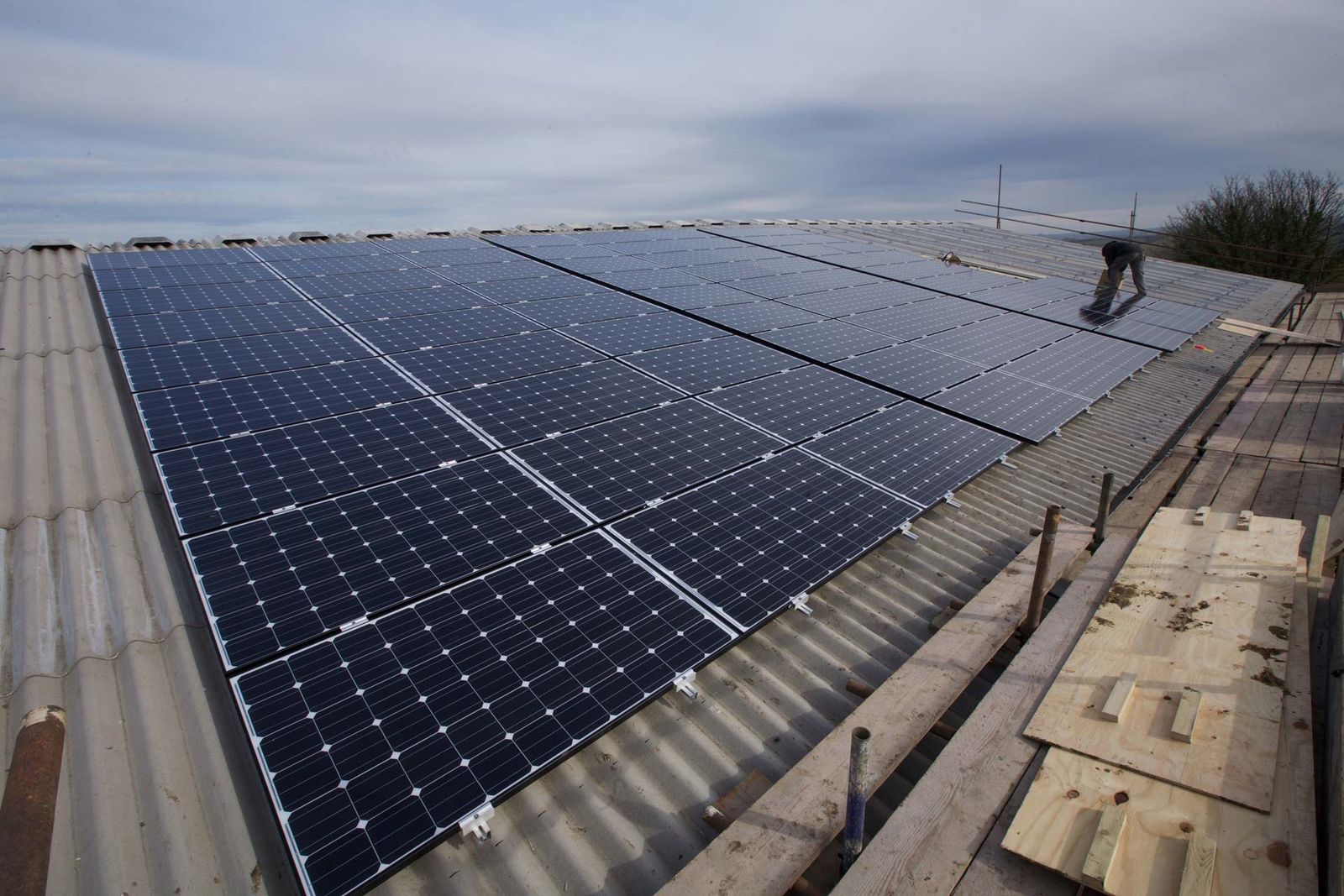 Long row of solar panels on a large agricultural building roof