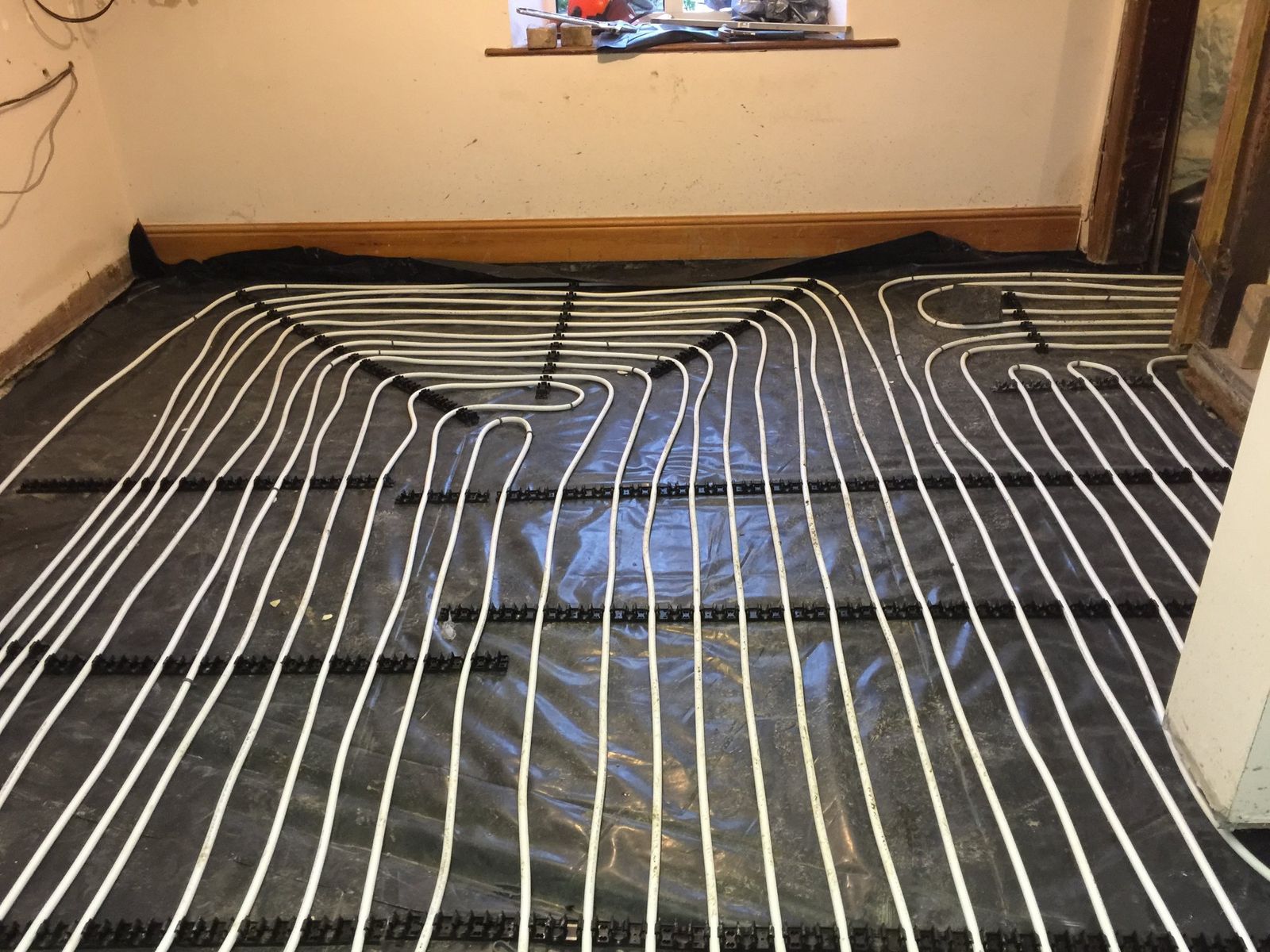 Underfloor heating pipes laid in a spiral pattern across a room before screeding