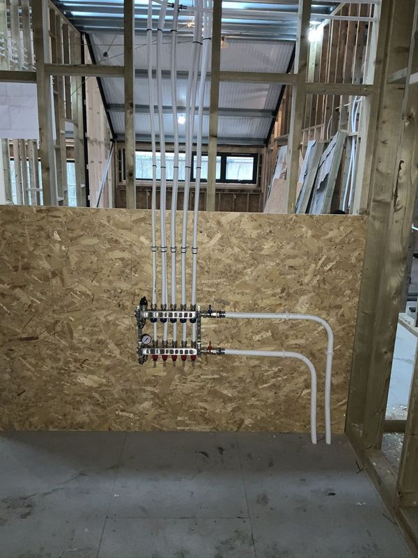 Manifold and pipe runs in a timber-framed building under construction