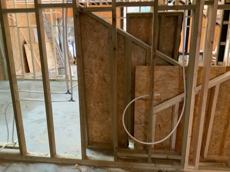 Timber-framed interior with insulation boards and pipework before finishing