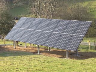 Ground-mounted solar array on a steel frame in a grassy field